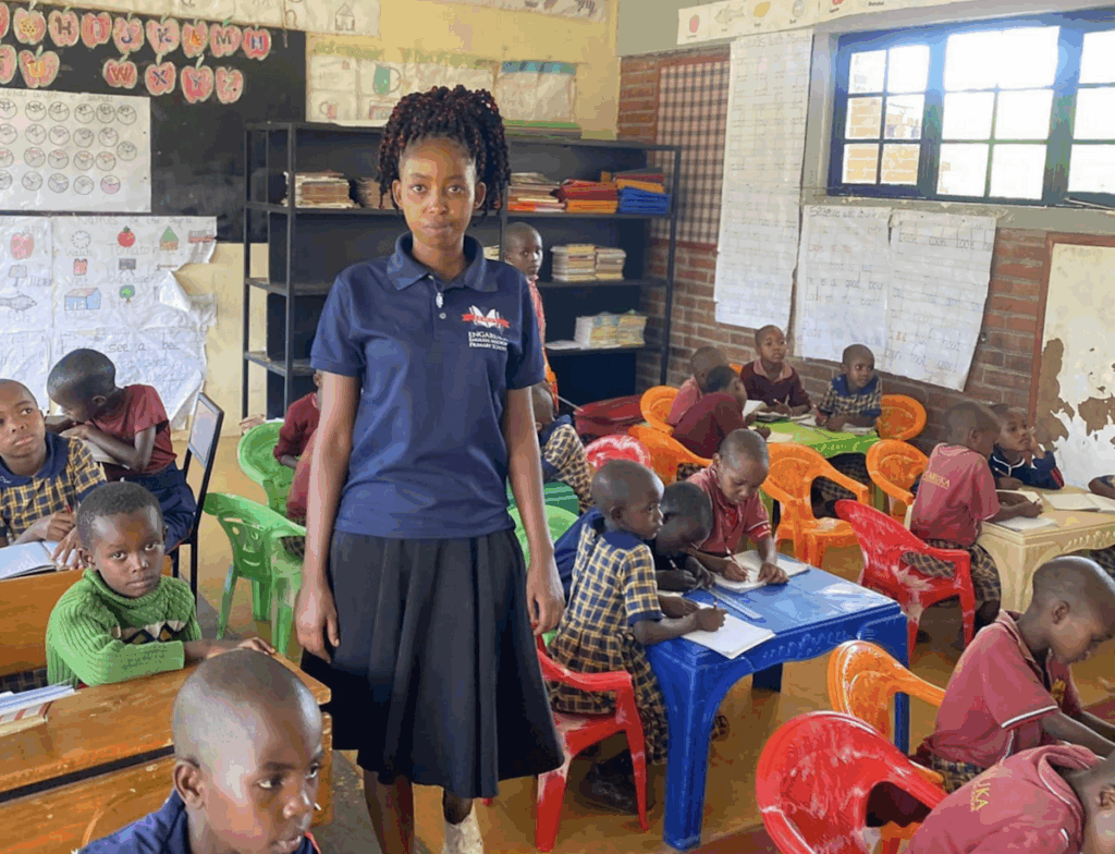 A woman standing in a classroom surrounded by students at desks